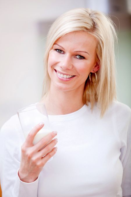 Beautiful woman holding a glass of milk and smiling