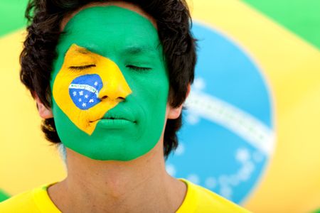 Portrait of a man with the Brazilian  flag painted on his face