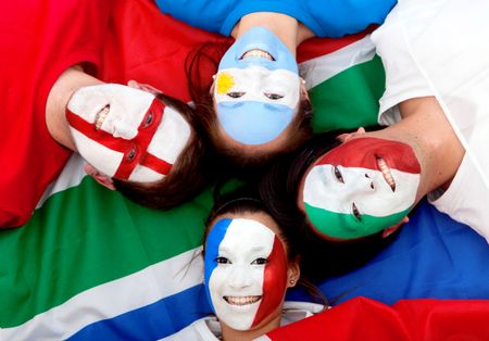 Group of football fans with painted faces lying over the South African flag