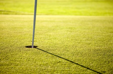 golf hole at sunset time - focus is on the hole