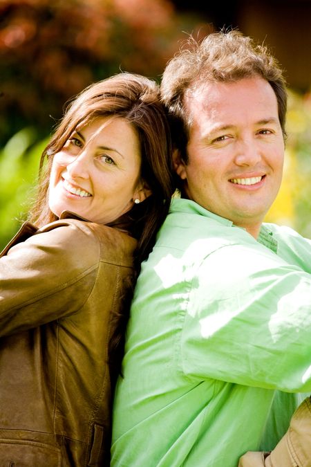 happy couple portrait outdoors smiling - back to back