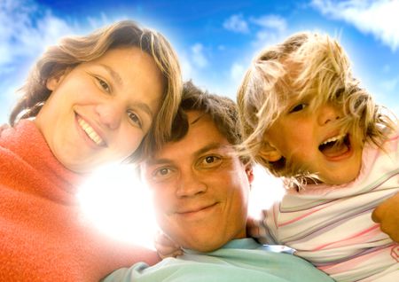 happy family portrait outdoors over a beautiful blue sky - sun flare behind the heads