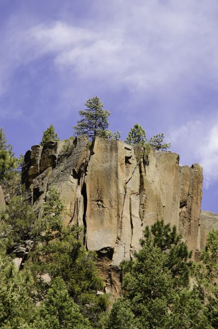 Cliff with pines under partly cloudy sky high in Jemez Mountains in northern New Mexico