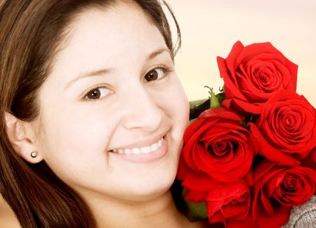beautiful girl smiling with red roses in sephia tones - focus is on the roses