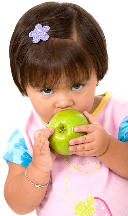 unhappy baby girl eating a green apple isolated over a white background