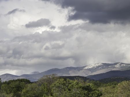 Moody sky over outskirts of Santa Fe in May, with snow on mountaintops