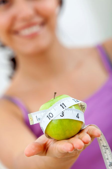 Woman holding an apple with a measure tape around it