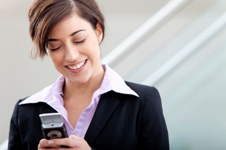 Business woman at the office texting from her cell phone