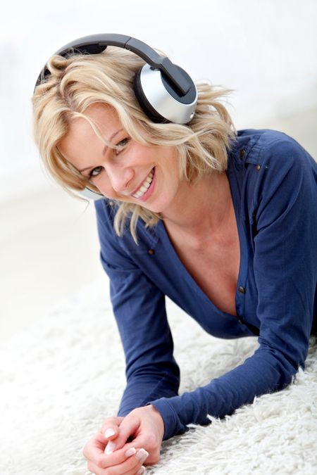 Woman lying on the floor listening to music and smiling