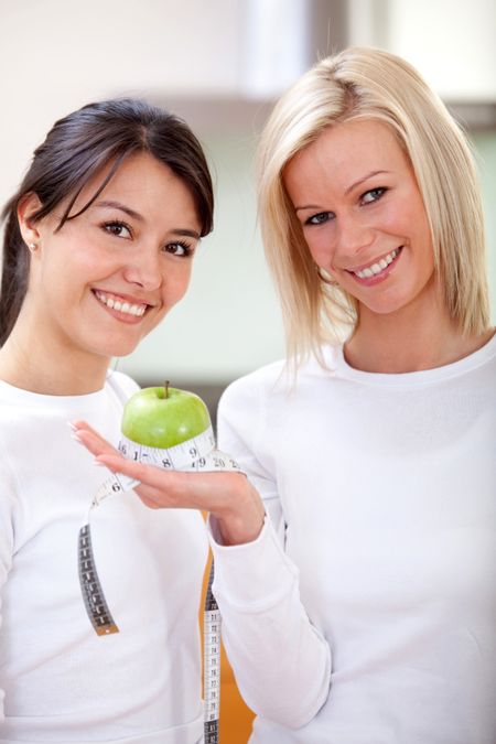 Women holding a green apple and smiling - indoors