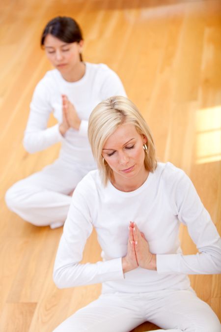 Women wearing white clothes doing yoga - indoors