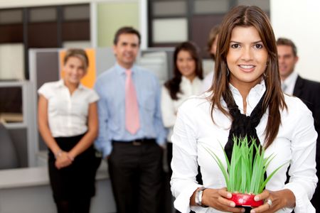 Business woman holding a plant at the office