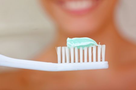 Woman holding a toothbrush in front of her face - blurry background