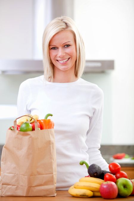 Shopping woman taking out groceries from a bag at home