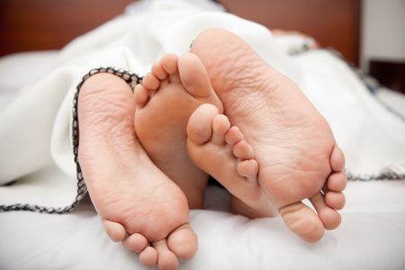 Feet of a couple lying in bed
