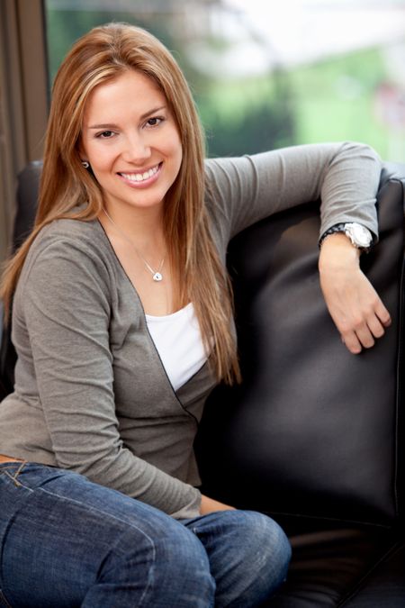 Beautiful woman at home sitting on a sofa and smiling