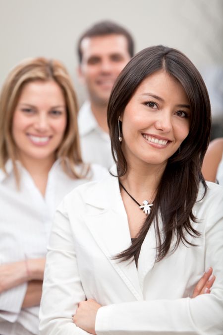 Business woman smiling with a group behind at the office