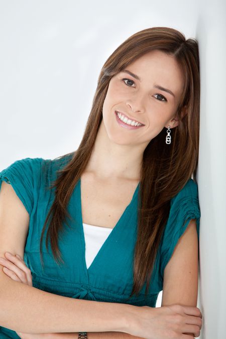 Beautiful woman portrait smiling and leaning against a wall