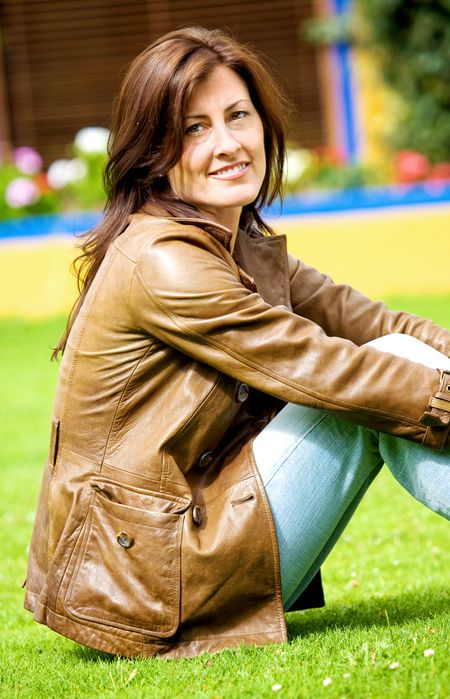 beautiful woman portrait smiling outside her home sitting on the grass