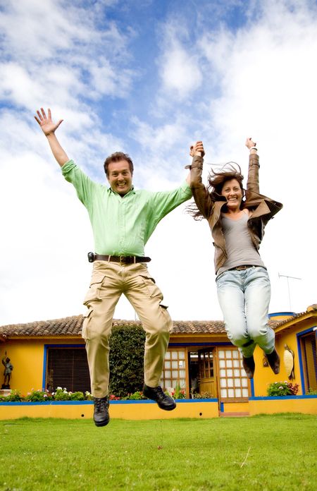 happy couple jumping of joy outside their home