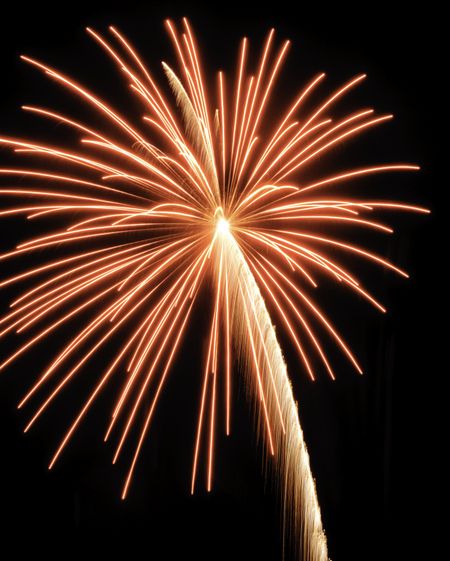 Reddish-yellow burst of fireworks with slightly arched rocket trail