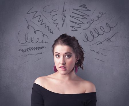 A cute female student making funny face expressions with pressure and problems in her head illustrated by drawn lines, marks and spirals on the urban wall background concept.