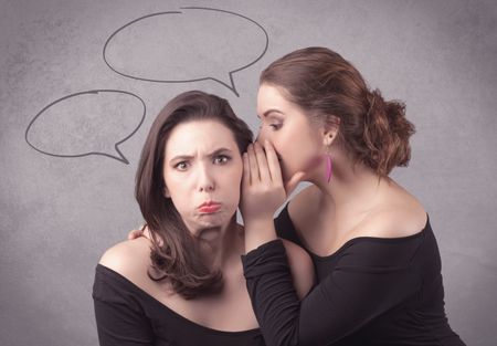 Two girls chatting and sharing their secrets concept with drawn chat bubbles on the background urban wall.