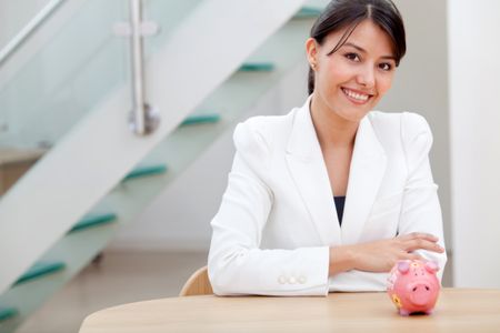 Beautiful business woman looking at a piggybank and smiling