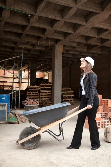 Female architech with a wheelbarrow at a construction site