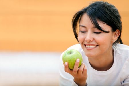 Beautiful woman holding an apple and smiling