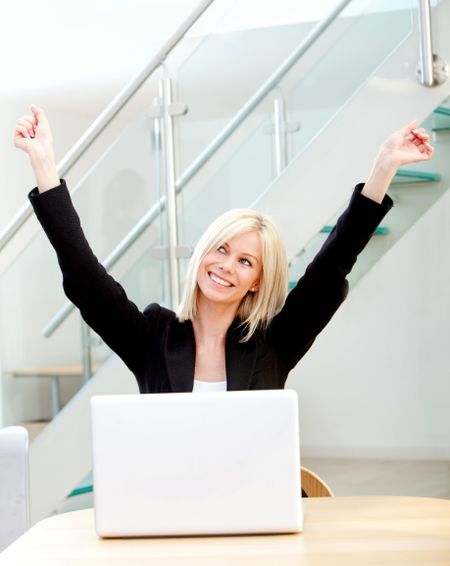 Happy business woman working on a laptop at the office
