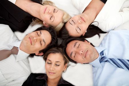 Group of business people with their heads together on the floor and eyes closed
