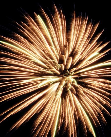 Yellow and orange burst of fireworks with feathery motion blur