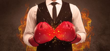 A strong sales person breaking something into pieces with red boxing gloves concept illustrated with glowing residue flying in the air.