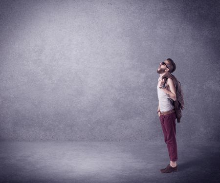 A hipster guy in stylish clothes shouting in front of an empty urban concrete wall background concept