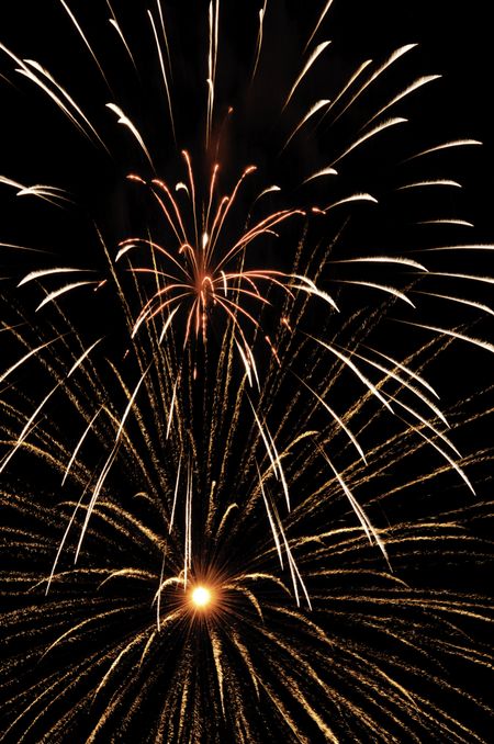 Burst of glittery fireworks with white-hot core below expanding cloud of white streaks