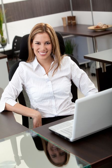 Business woman sitting at her desk in the office with a laptop