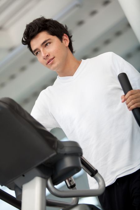 Beautiful gym man exercising on a cardio machine smiling