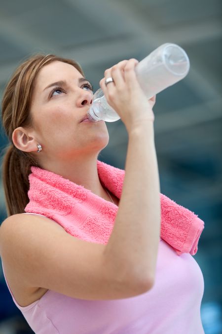 Beautiful athletic woman at the gym drinking water from a bottle