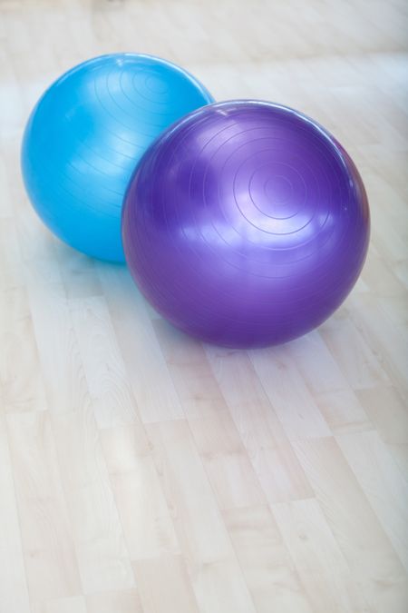 Couple of colorful pilates balls on a wooden floor - fitness equiment