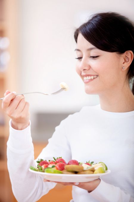 Woman eating with fruits and smiling - healthy lifestyle
