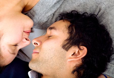 Beautiful couple on the floor with eyes closed facing at each other