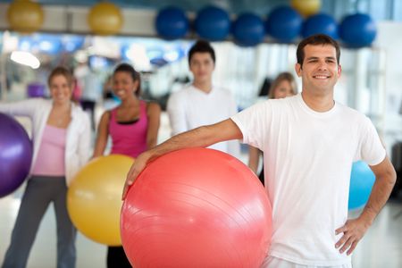 Group of people at the gym smiling with a pilates ball