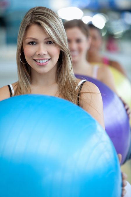 Woman with a group at the gym smiling with a pilates ball