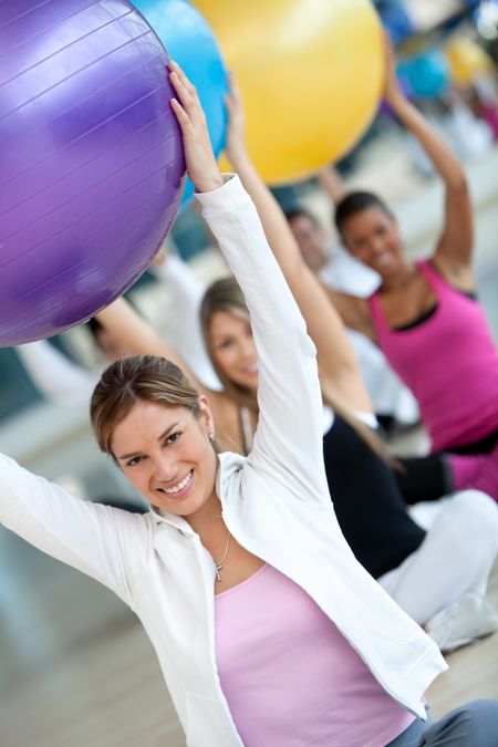 Group of people at the gym smiling with a pilates ball