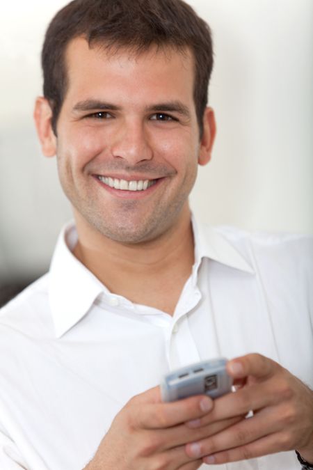Business man texting on his cell phone and smiling - indoors