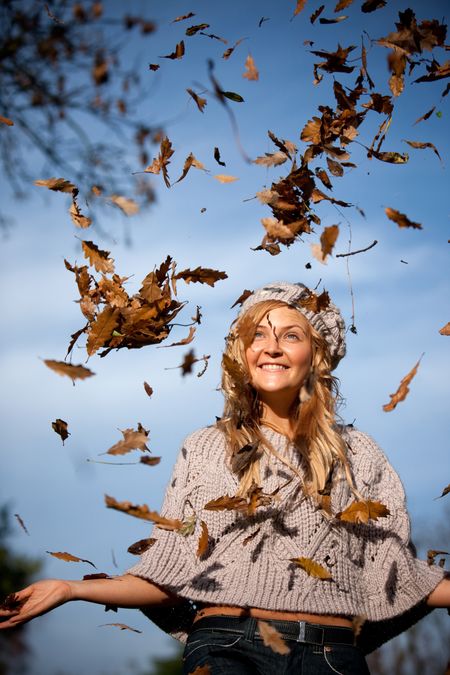 Beautiful autumn woman with leaves falling from the tree