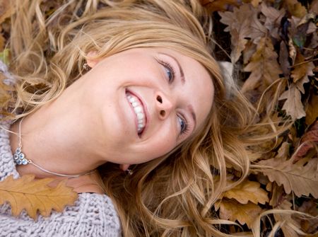 Beautiful autumn woman lying on the floor with leaves around her head