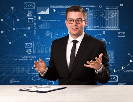 Young handsome businessman sitting at a desk with blue charts and data behind him