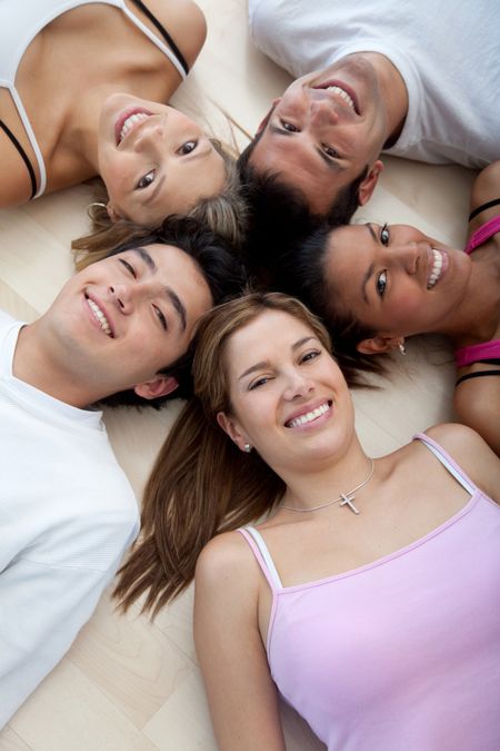 Athletic group of people lying on the floor with heads together